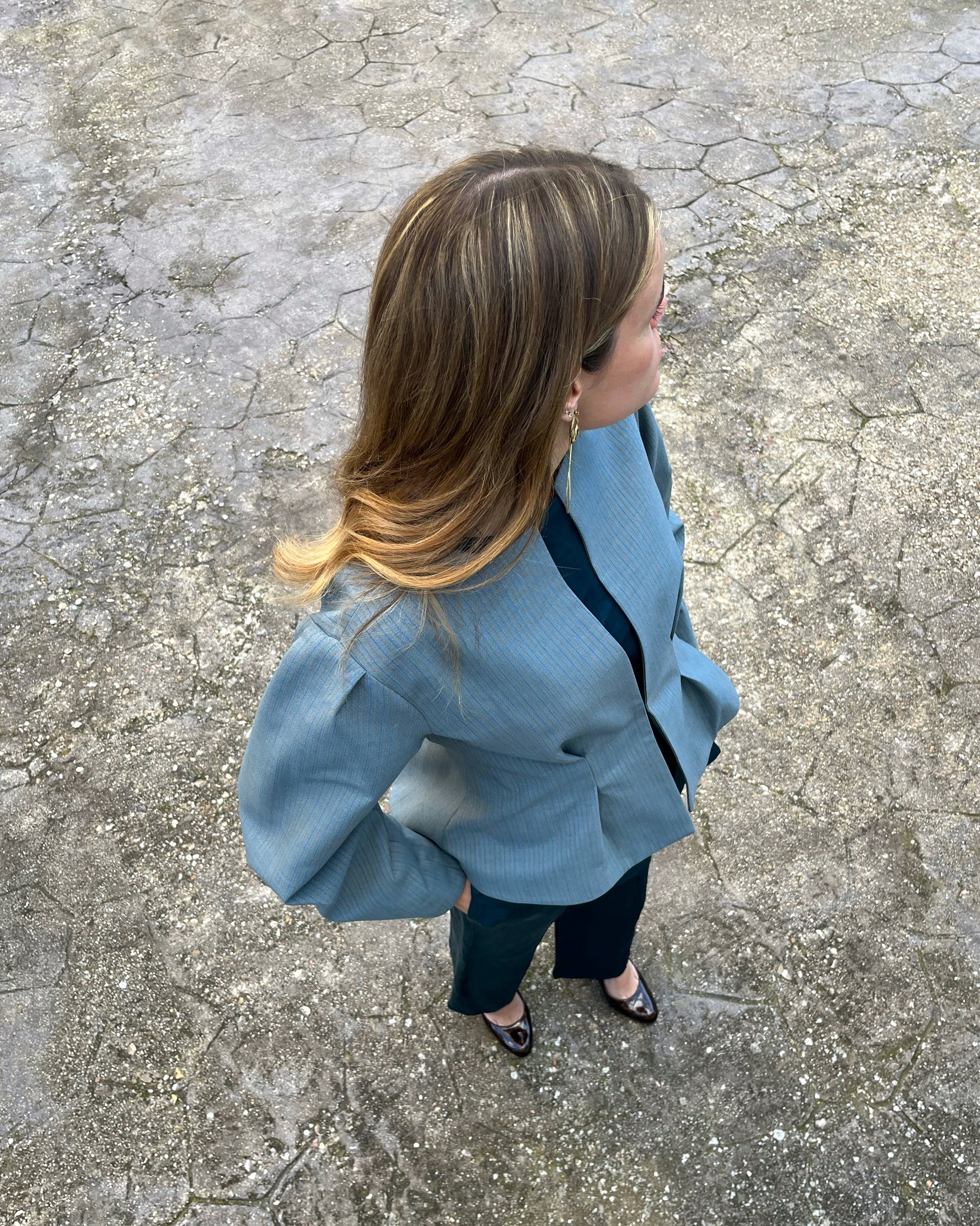 Vista cenital de chaqueta azul elegante de mujer con rayas a tono; modelo en jardín.