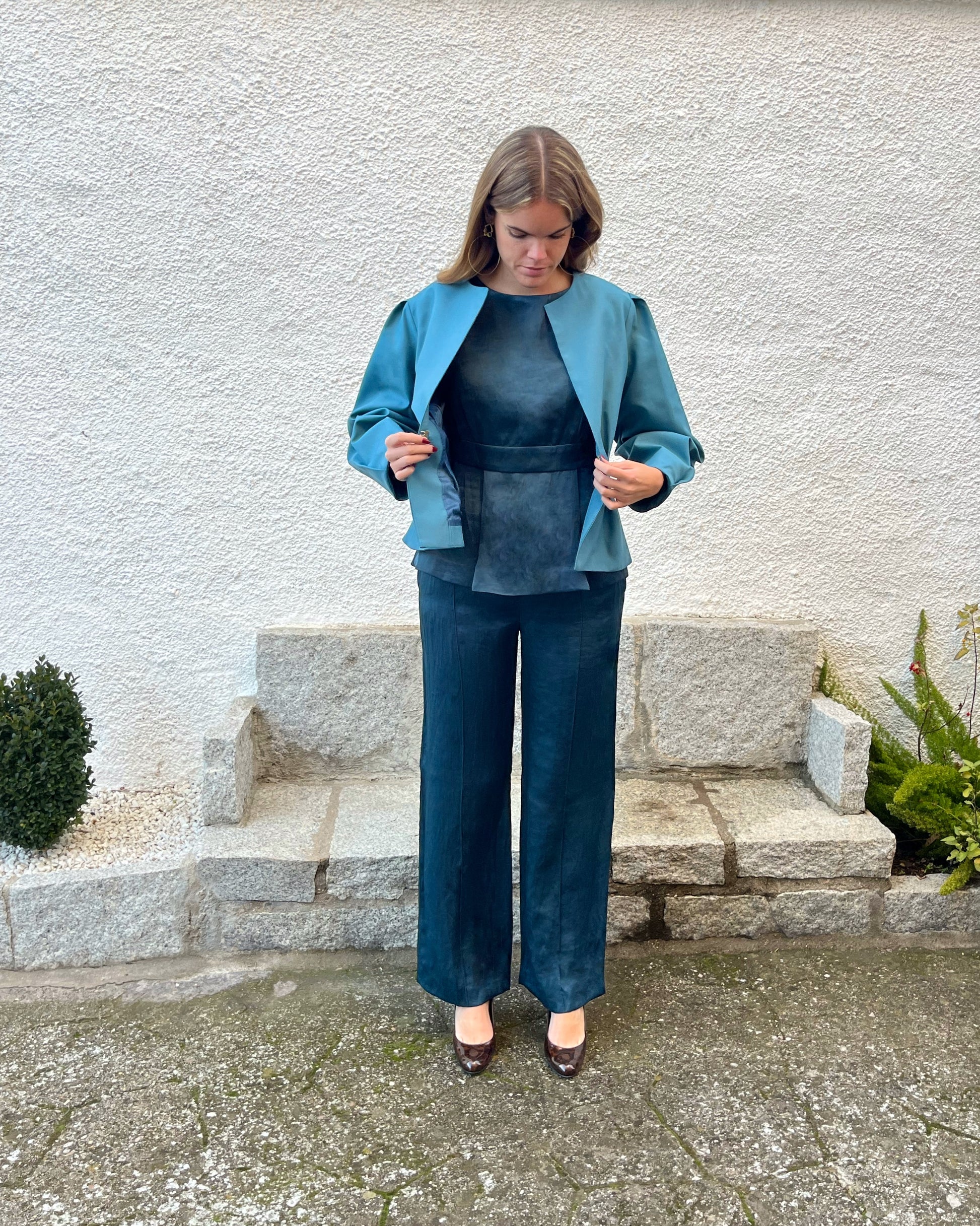 Detalle del forro azul petróleo y exterior de la chaqueta azul turquesa; diseño elegante de mujer en jardín.