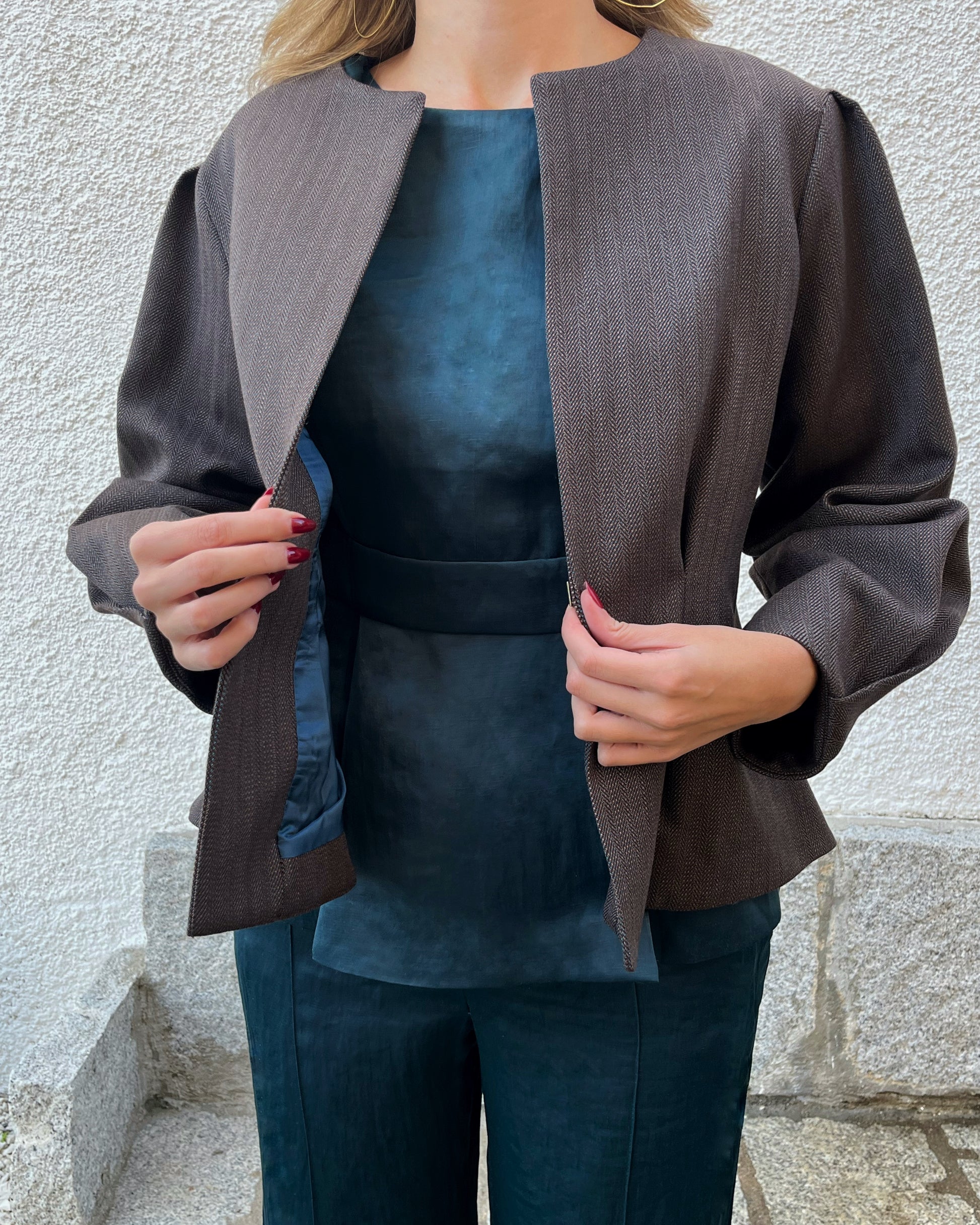 Detalle del forro azul petróleo y exterior de la chaqueta de espiga marrón y azul; diseño elegante de mujer en jardín.