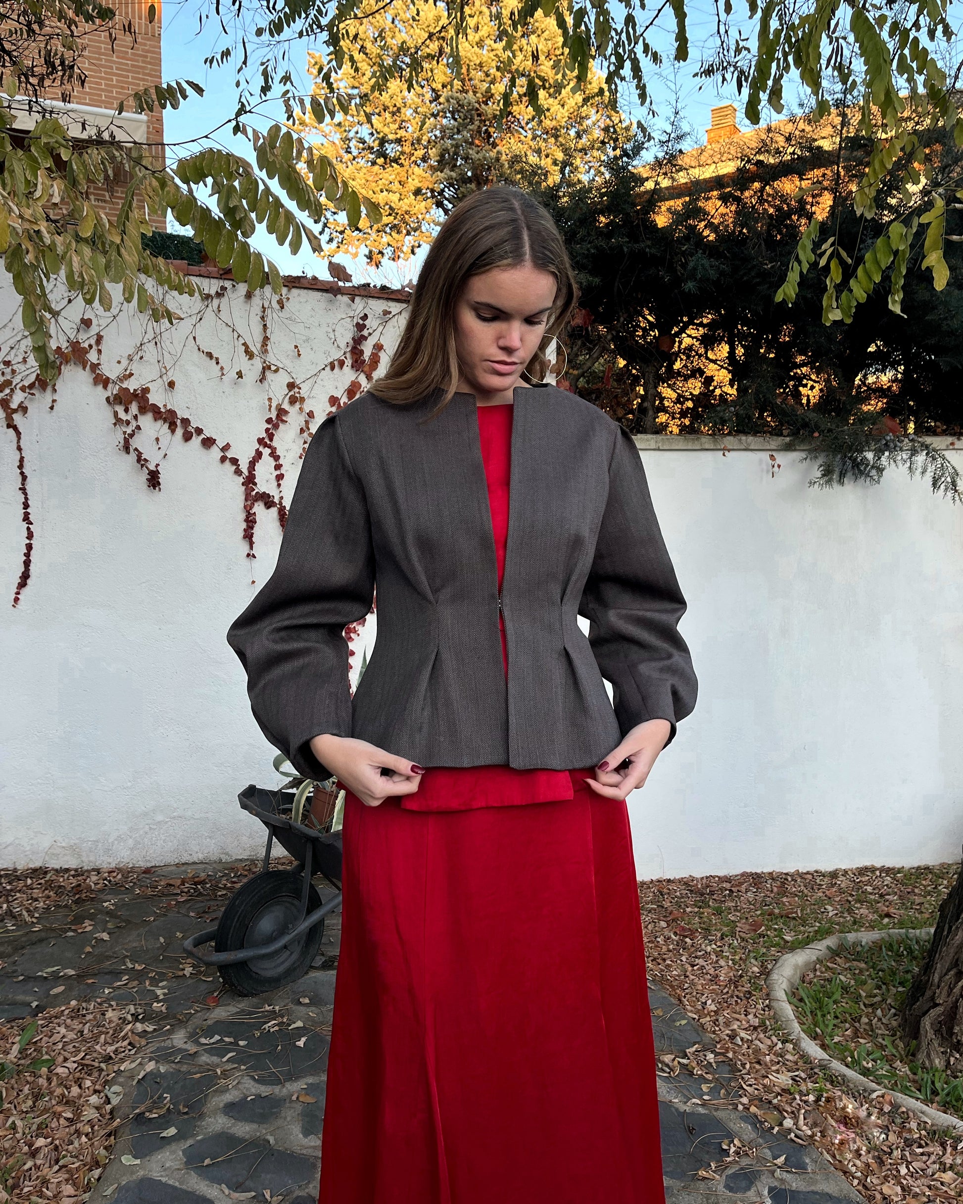 Chaqueta de mujer con textura de espiga en marrón y azul, diseño elegante entallado; vista frontal con modelo en jardín.