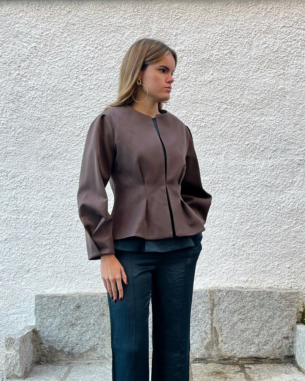 Chaqueta marrón de mujer con textura de lunares, diseño elegante entallado de la colección Historia de un sastre; vista frontal con modelo en jardín.