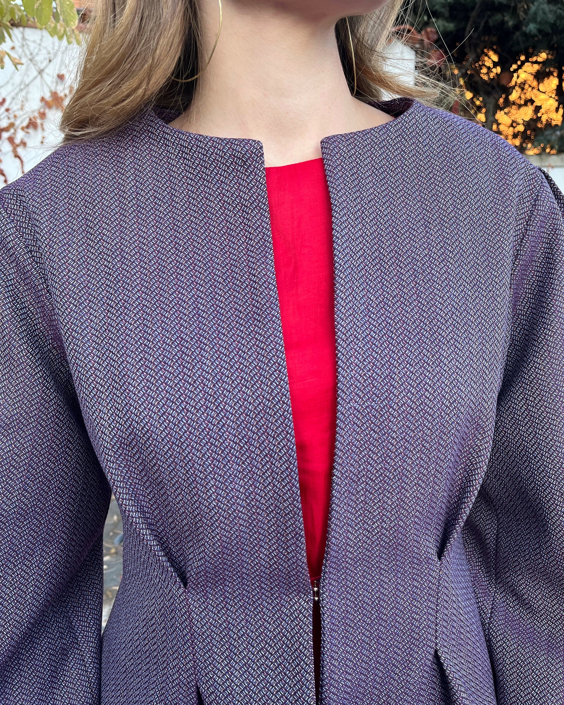 Detalle en zoom de chaqueta morada con textura de espiga y broche dorado oculto; diseño elegante de mujer, colección Historia de un sastre.