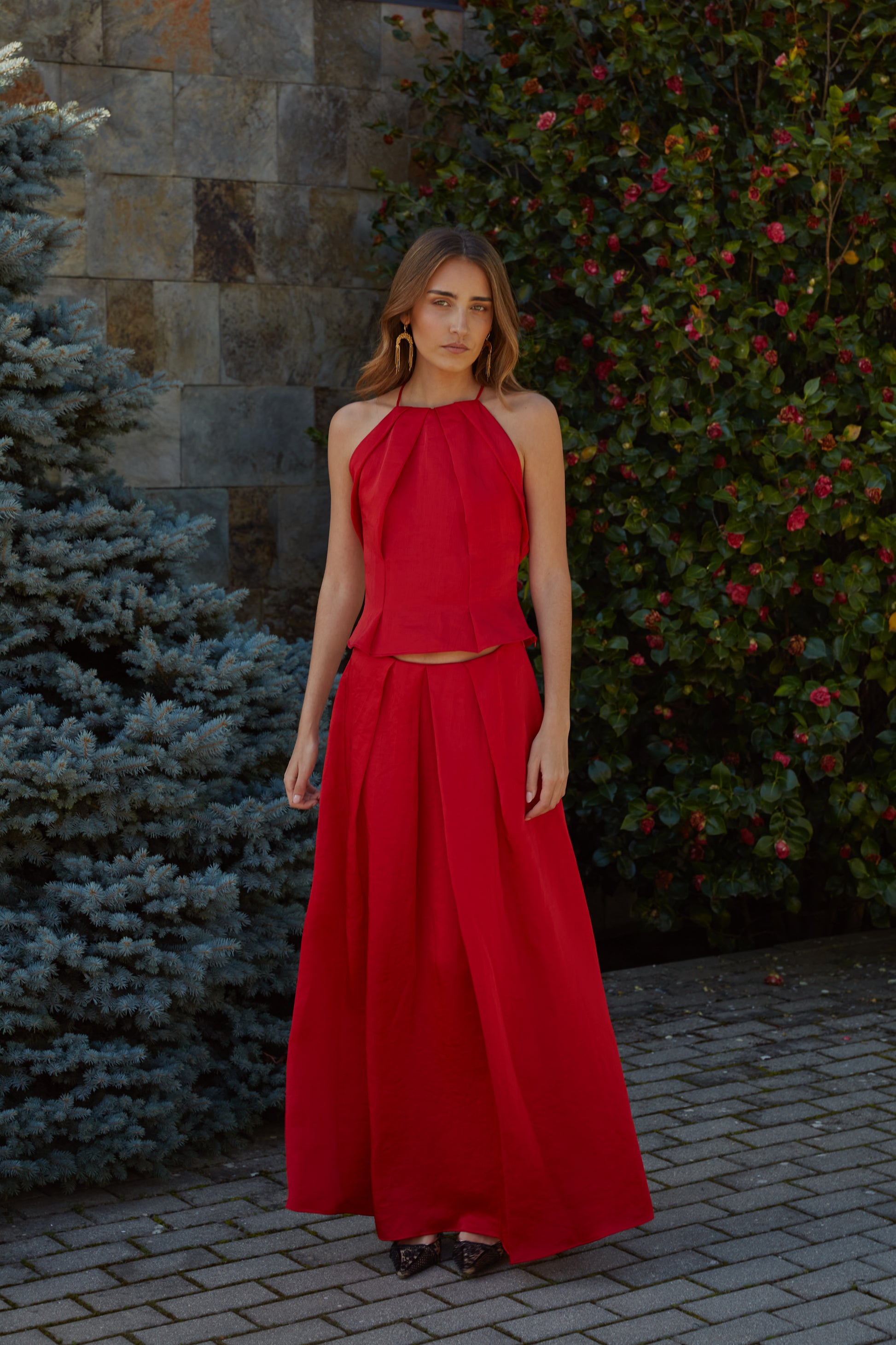 Conjunto rojo elegante de mujer con top halter plisado y falda Beatriz de tiro alto; look de invitada ideal para eventos en jardín.