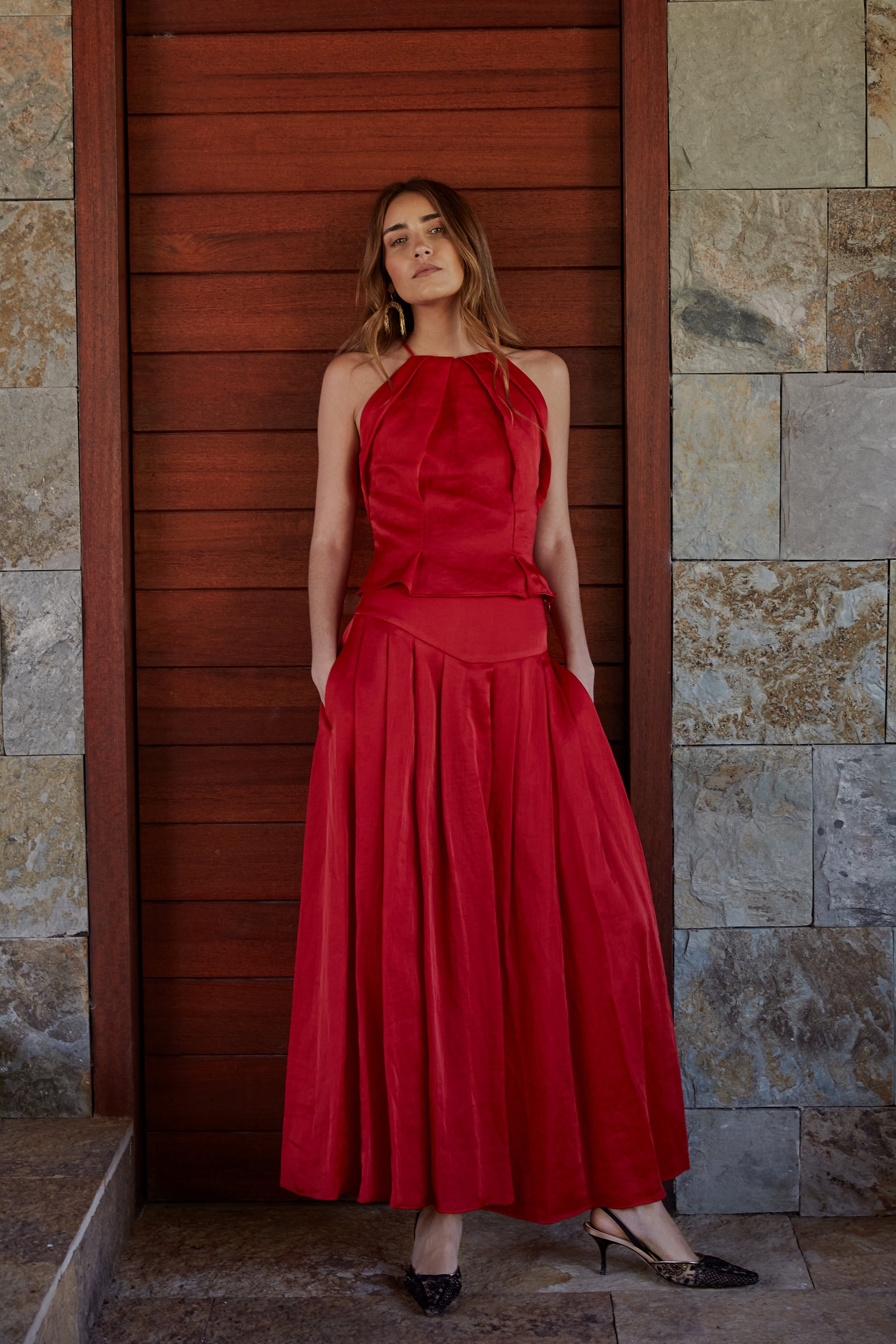 Conjunto rojo elegante de mujer con top halter plisado y falda María de tablas de tiro medio; look de invitada ideal para eventos.