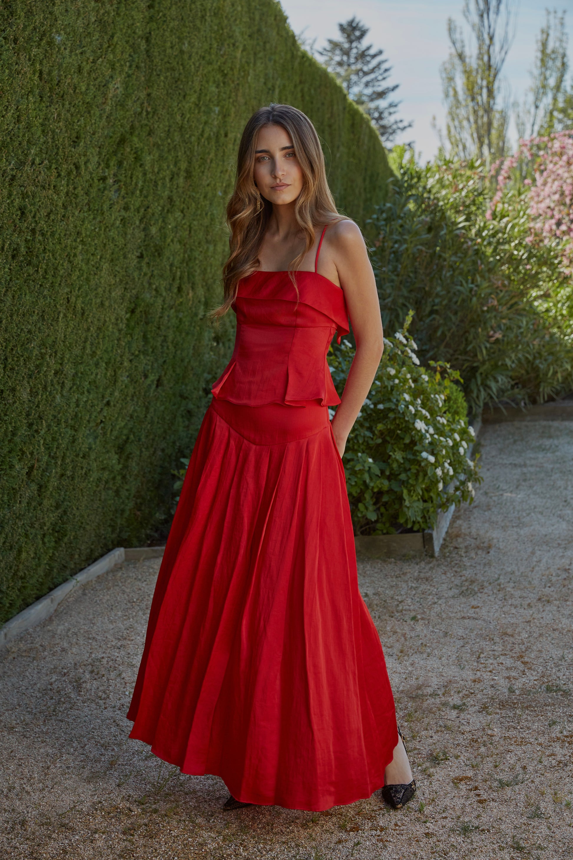 Conjunto rojo de invitada con top de tirantes finos Elena y falda Beatriz de tiro medio; look elegante de mujer para eventos en jardín.