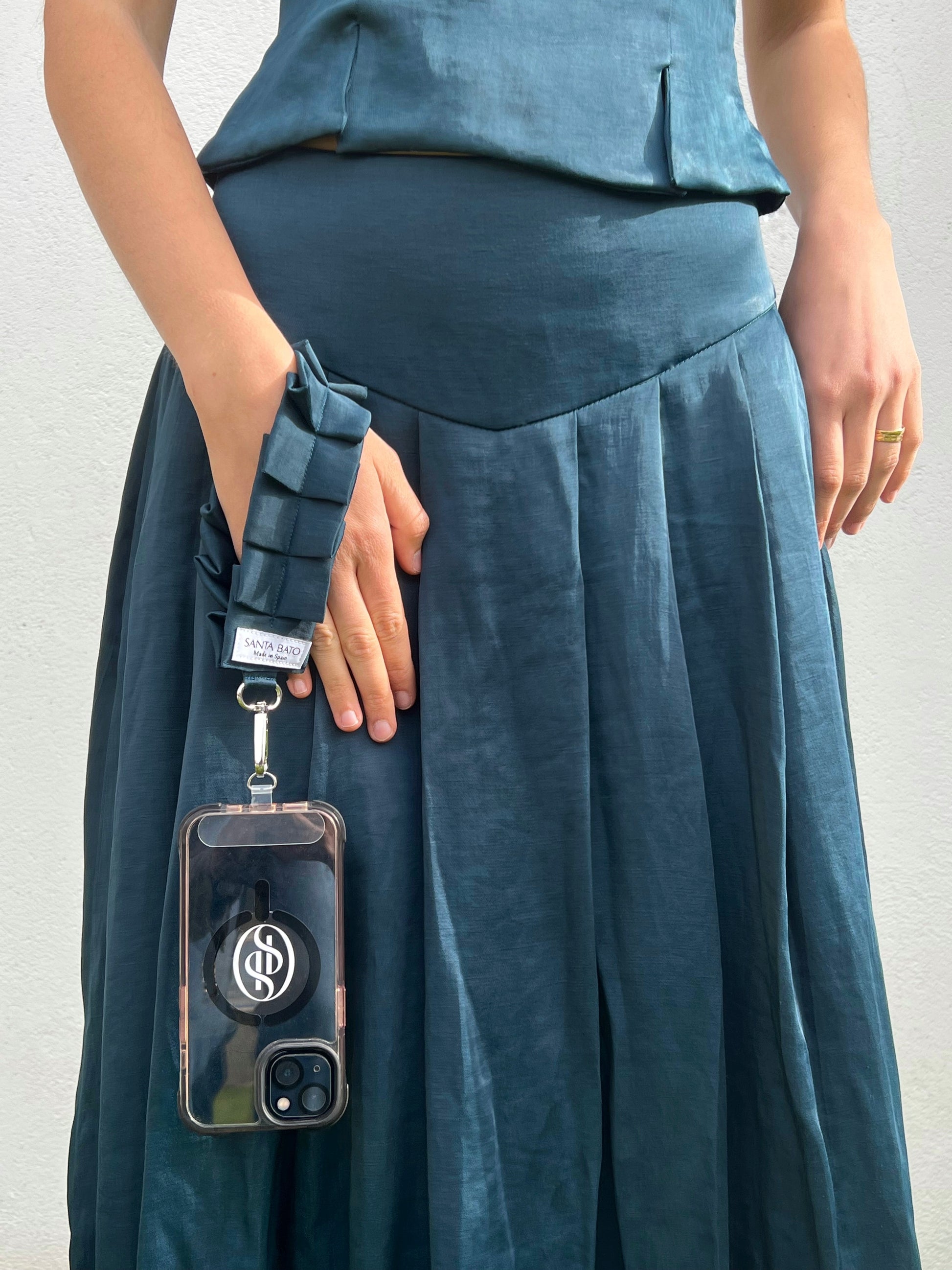 Mujer con teléfono sujeto a correa azul plisada, complemento de moda ideal para eventos y ocasiones especiales