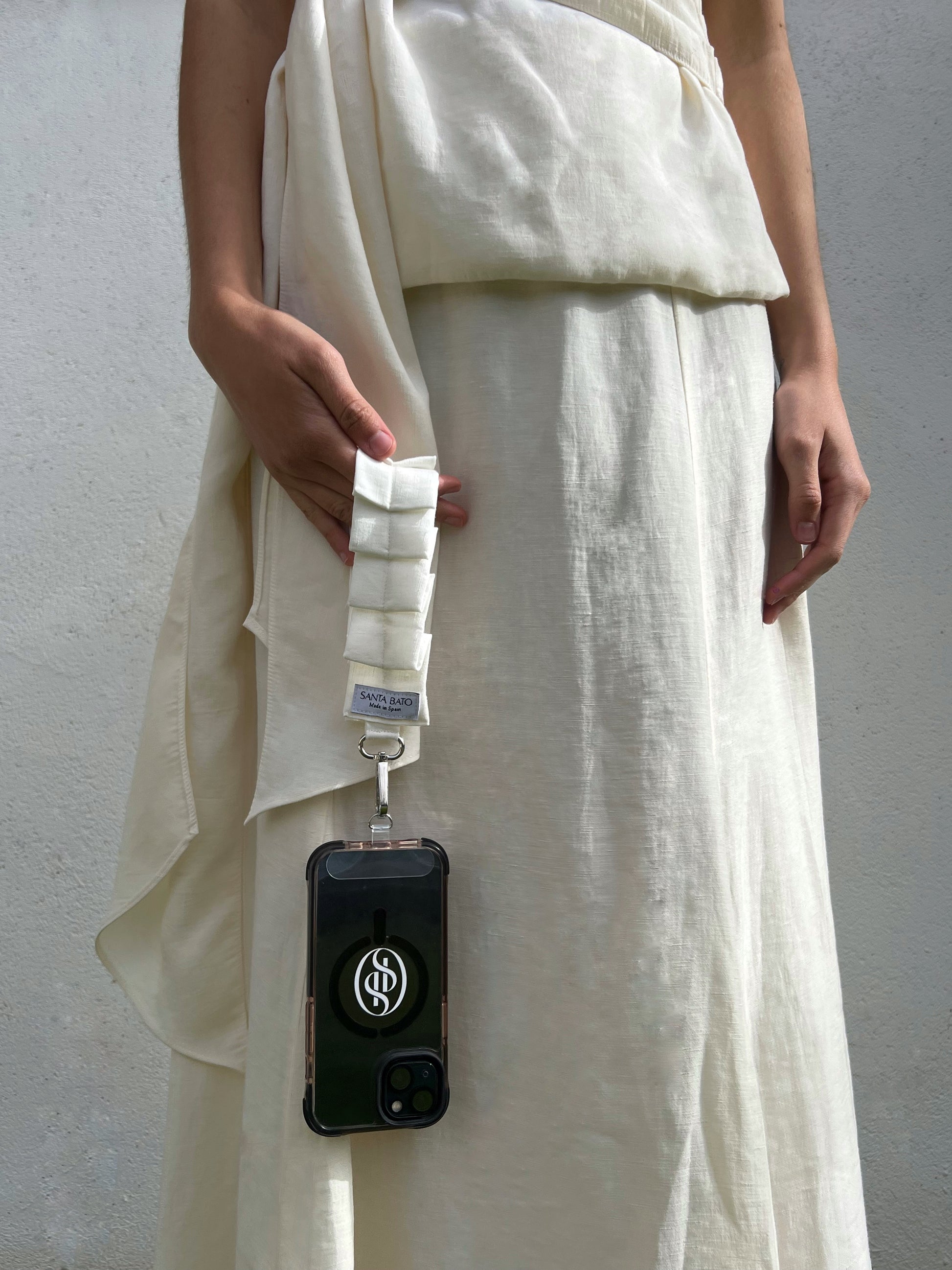 Mujer con teléfono sujeto a correa blanca plisada, accesorio de moda perfecto para eventos