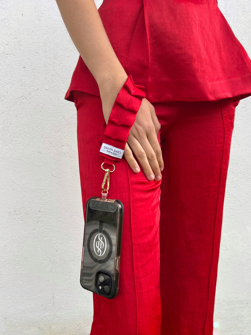 Mujer con correa de móvil roja plisada, complemento de moda ideal para invitadas y eventos