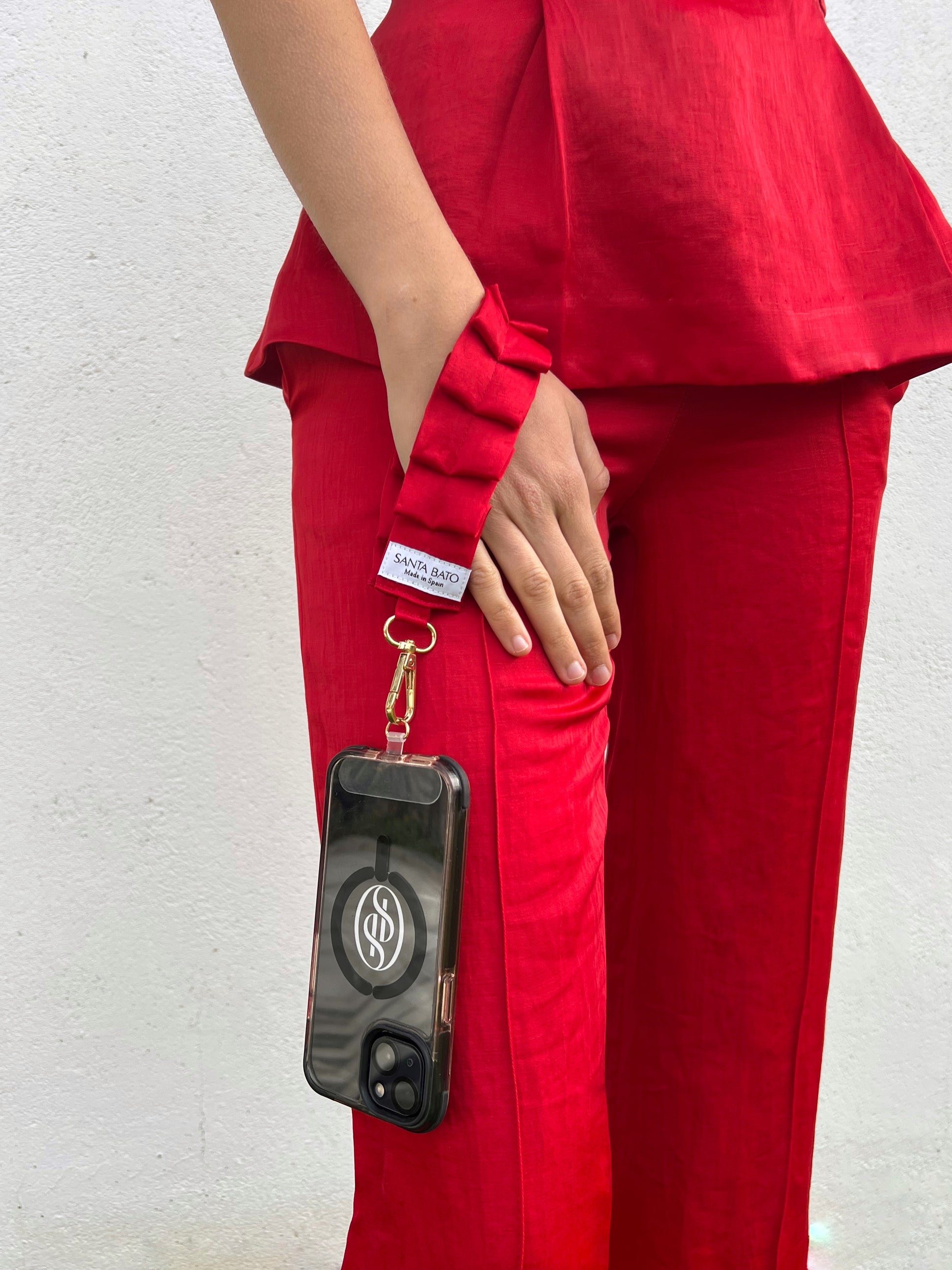 Mujer con correa de móvil roja plisada, complemento de moda ideal para invitadas y eventos
