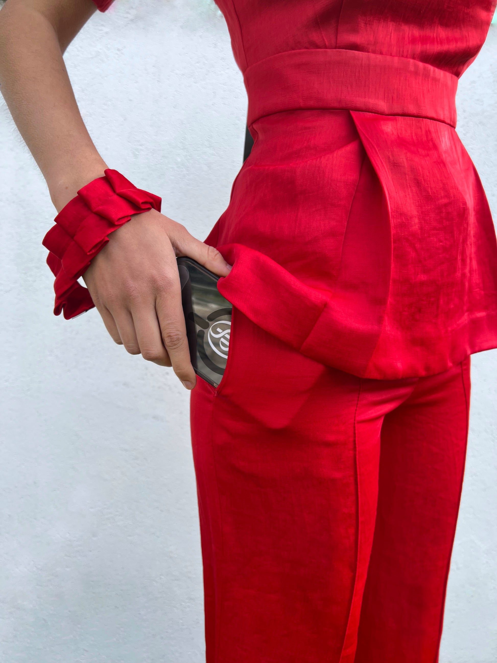 Mujer guardando móvil con correa roja plisada, accesorio de moda práctico y elegante