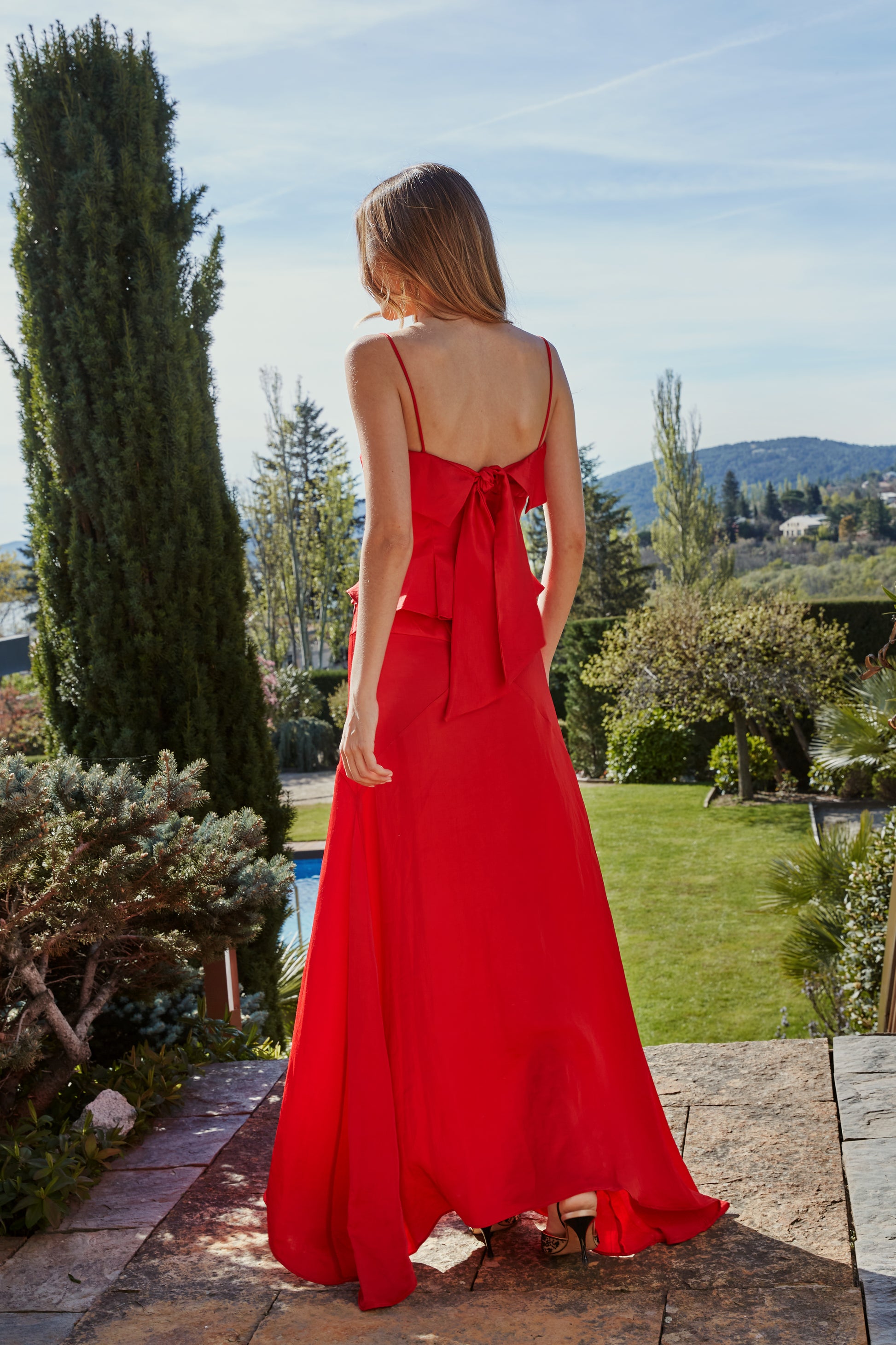 Vista trasera de falda rojo fluida de mujer con godets que aportan vuelo y movimiento; diseño elegante para eventos.