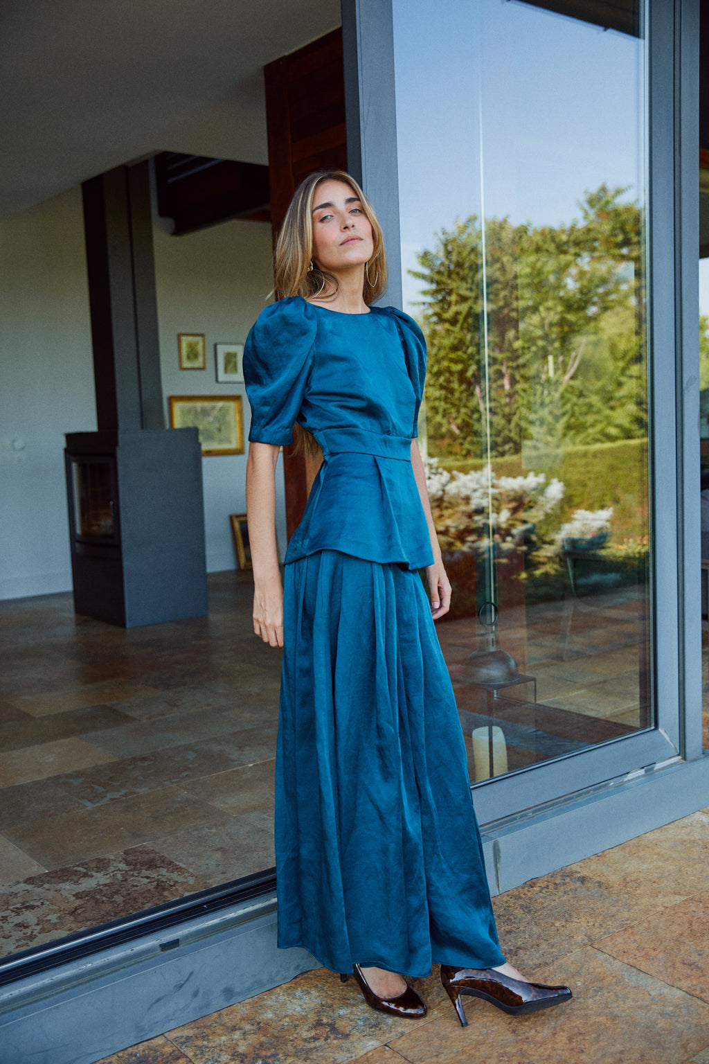 Look invitada con falda larga azul petróleo y top con mangas abullonadas, conjunto ideal para eventos.