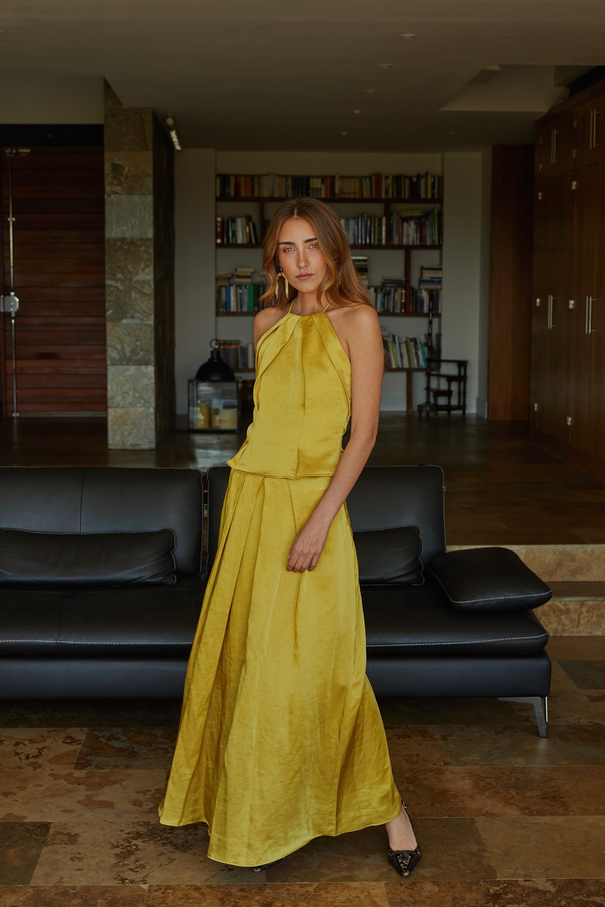 Vista lateral de falda larga color aceite amarillo verde dorado fluida de mujer con tiro alto y movimiento elegante; prenda ideal para invitadas.