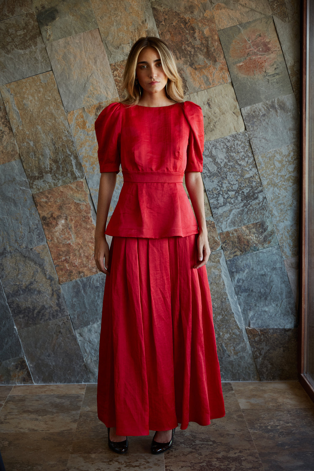 Look invitada con falda larga roja y top con mangas abullonadas, conjunto ideal para eventos.