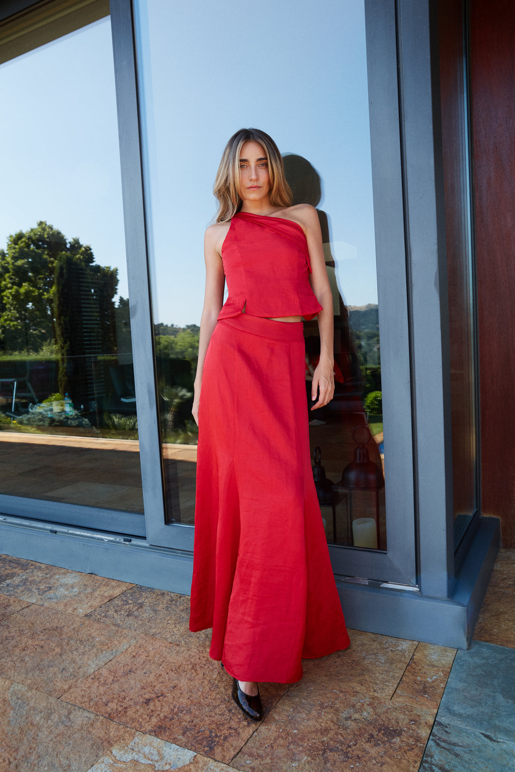 Conjunto sofisticado de falda con godets y top asimétrico rojo, ideal para eventos de noche.