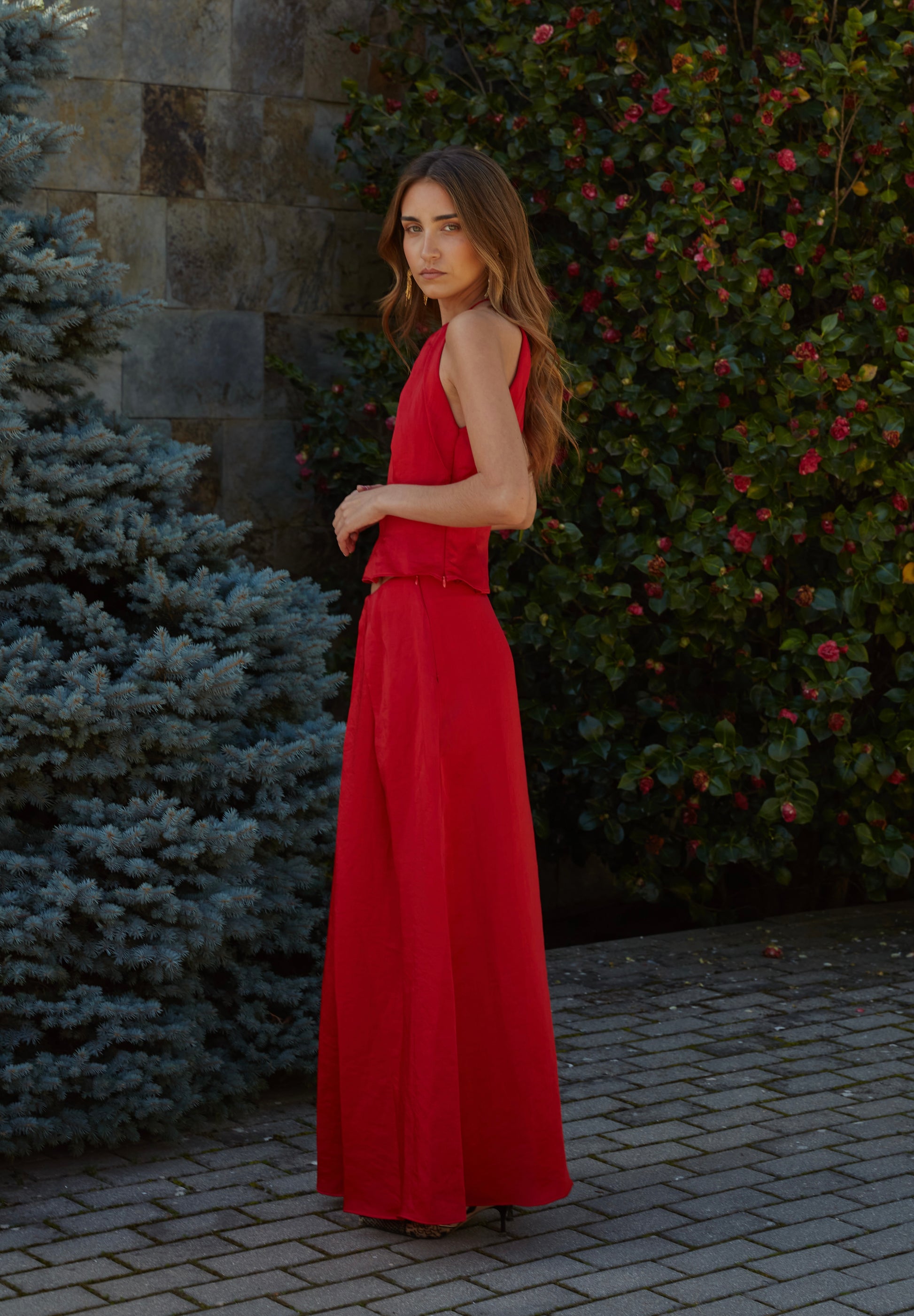 Vista lateral de falda larga rojo fluida de mujer con tiro alto y movimiento elegante; prenda ideal para invitadas.