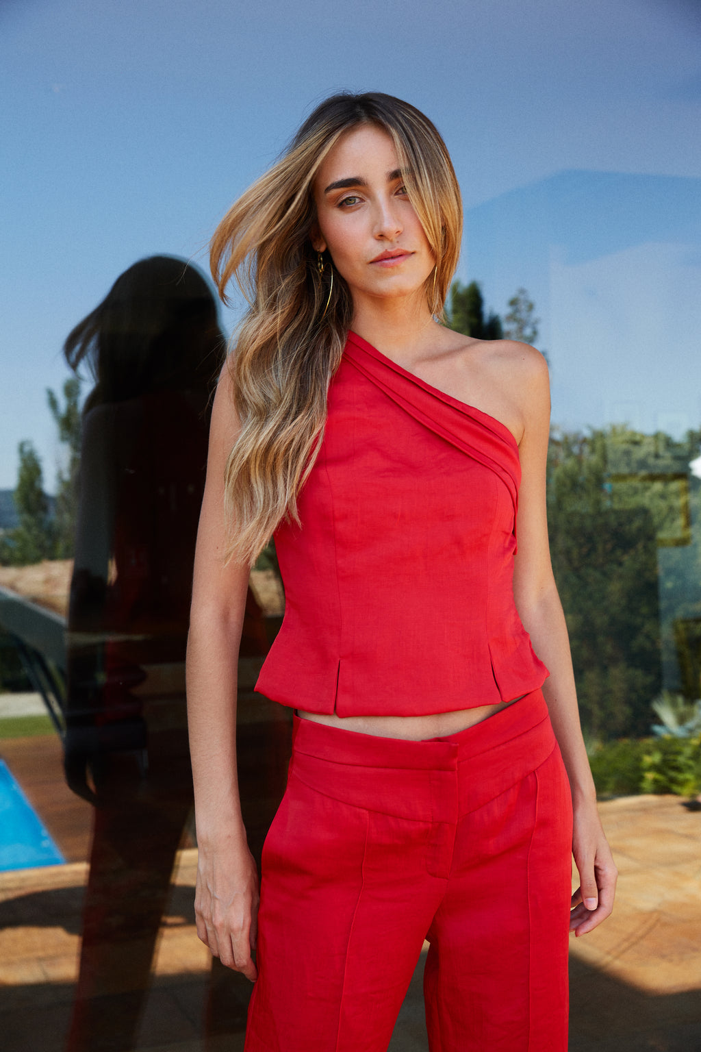 Pantalón rojo con canesú en pico y pernera ancha, vista detalle frontal.