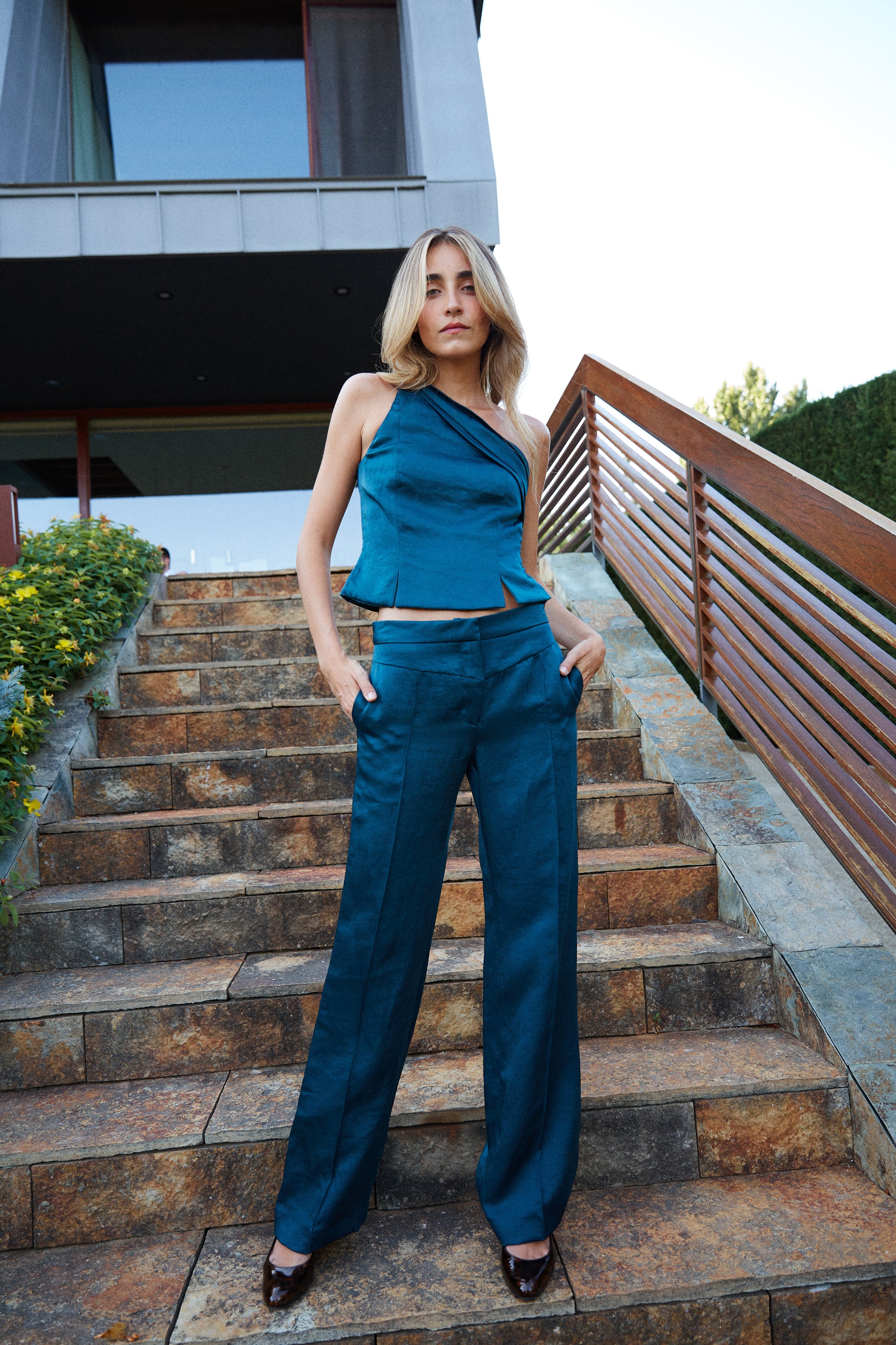 Conjunto elegante con top azul petróleo plisado y pantalón de pernera ancha, ideal para eventos.