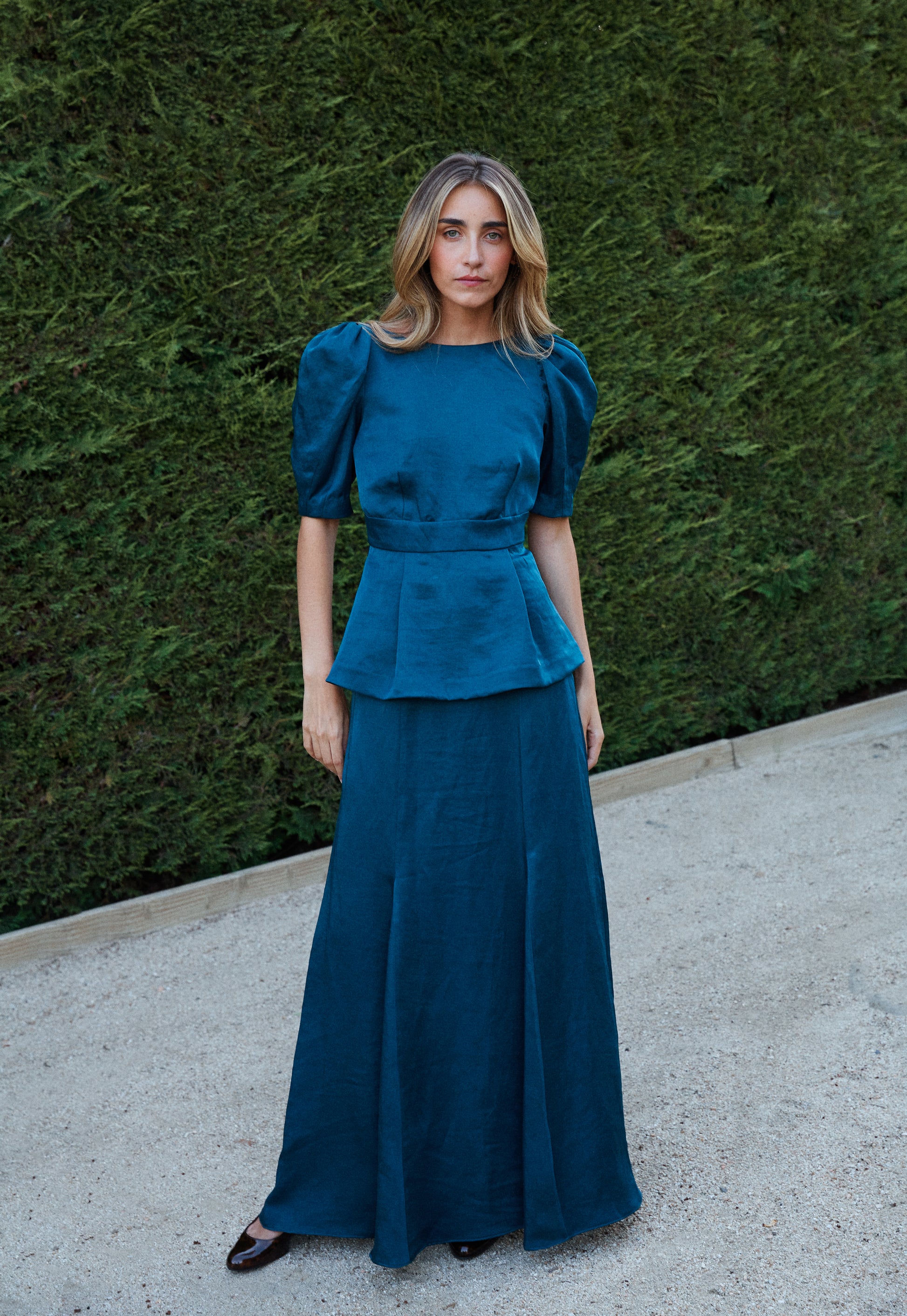 Look de fiesta con top azul petróleo abullonado y falda fluida con godets, outfit sofisticado.