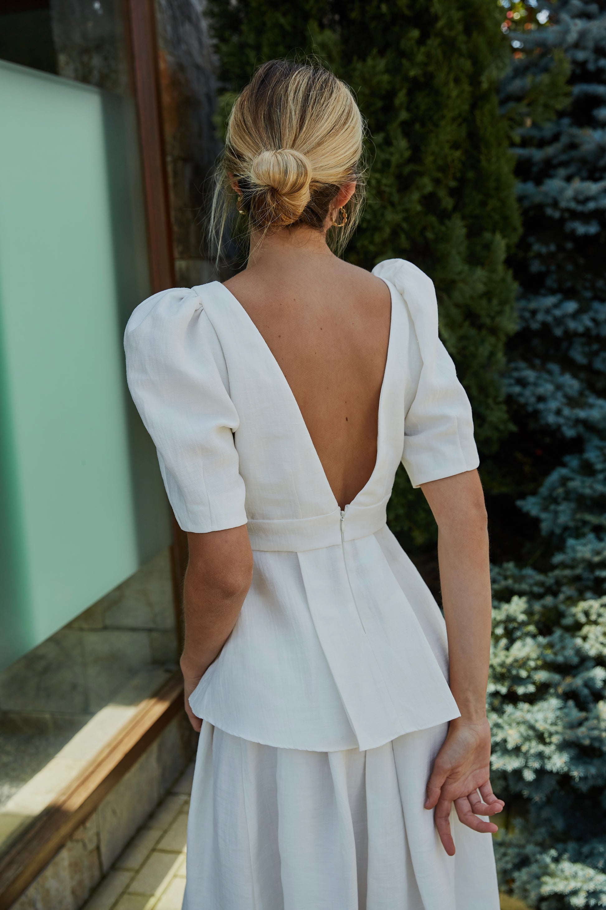 Top blanco con mangas abullonadas y escote en pico, vista frontal, ideal para eventos elegantes.