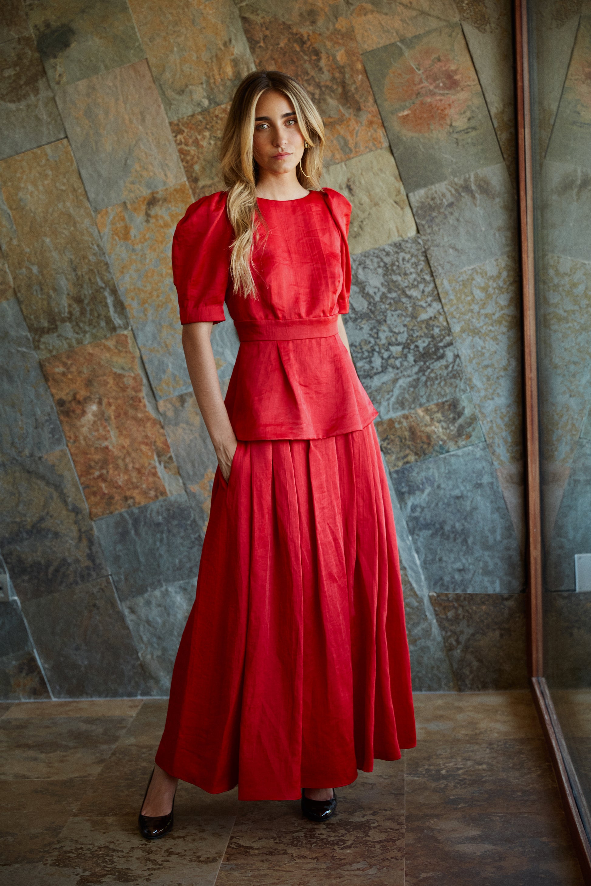 Conjunto de top rojo elegante con falda de tablas, ideal para eventos especiales.